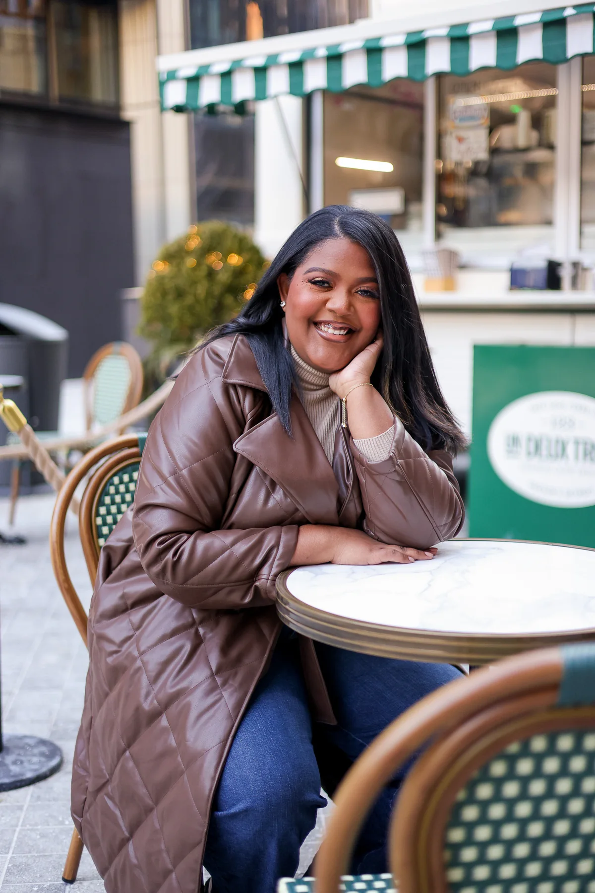 Kendra Taylor smiling warmly at a sunlit café table